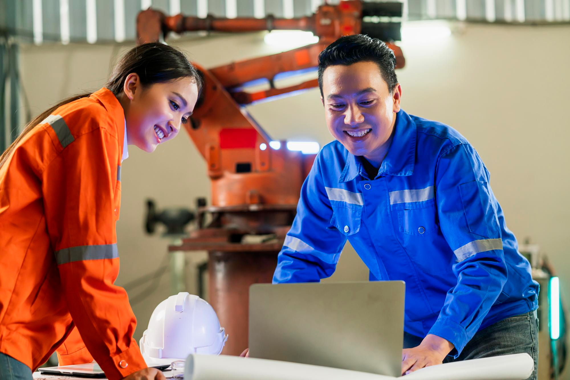 Engineers collaborating beside automated manufacturing equipment